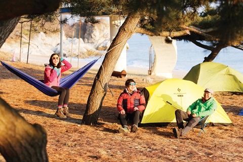 바닷가에서 텐트를 치고 백패킹을 즐기는 사람들. 

