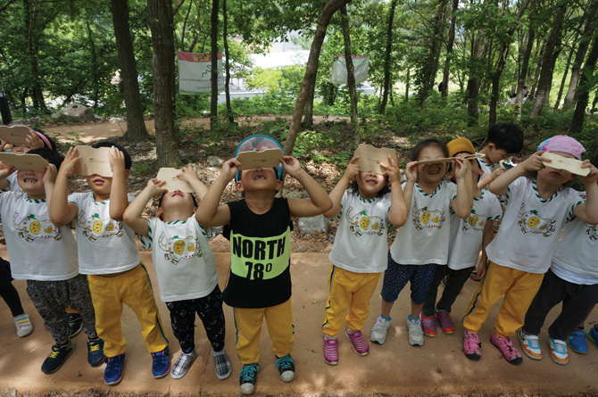 칠곡숲체원 토리유아숲체험원에서 진행하는 프로그램에 참가한 어린이들이 기구를 이용해서 숲을 관찰하고 있다. 