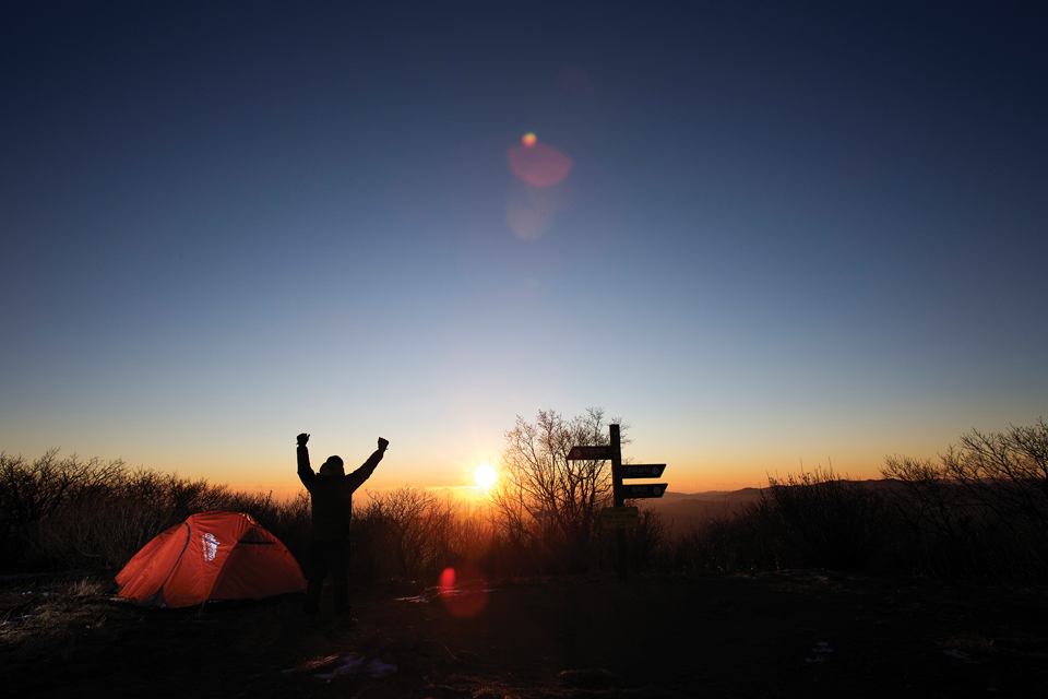 두타산에서 텐트를 치고 밤새 기다린 일출 등산객이 떠오르는 태양을 향해 두 팔을 번쩍 들고 있다.