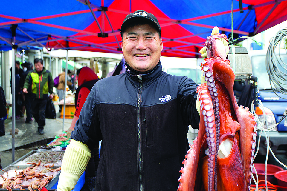 문어를 들어보이며 사람 좋은 웃음을 짓는 북평민속시장 어물전의 김석호씨. 
