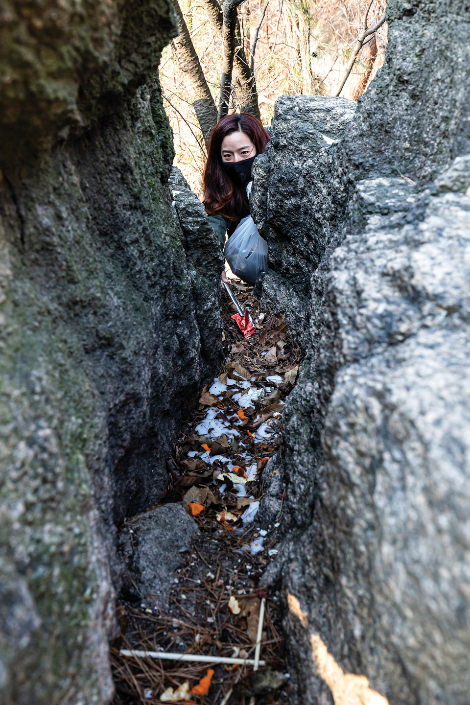 바위 틈새에 귤껍질과 젓가락들을 수거하고 있는 김강은씨.