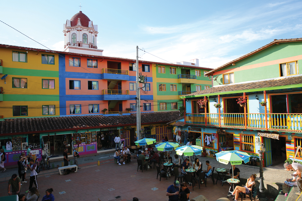 모든 벽, 창틀, 지붕까지 밝고 강렬한 색상으로 칠해진 구아타페마을의 중앙광장에서 여행자들이 한가로이 시간을 보내고 있다.