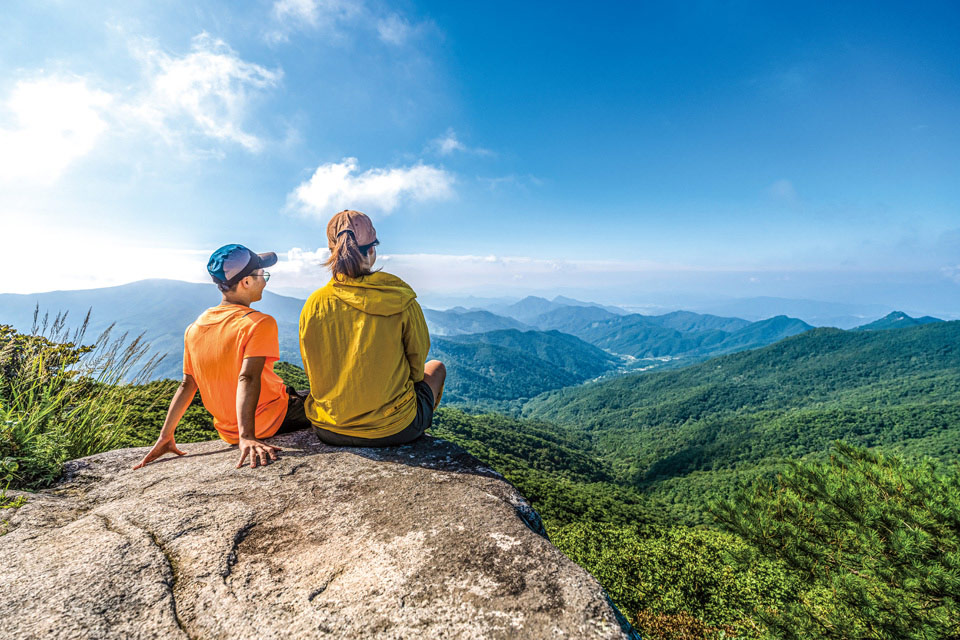 정상 바위에 걸터앉아 산세를 내려다본다.